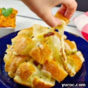 hand pulling a piece of Cheesy pull apart bread from bun