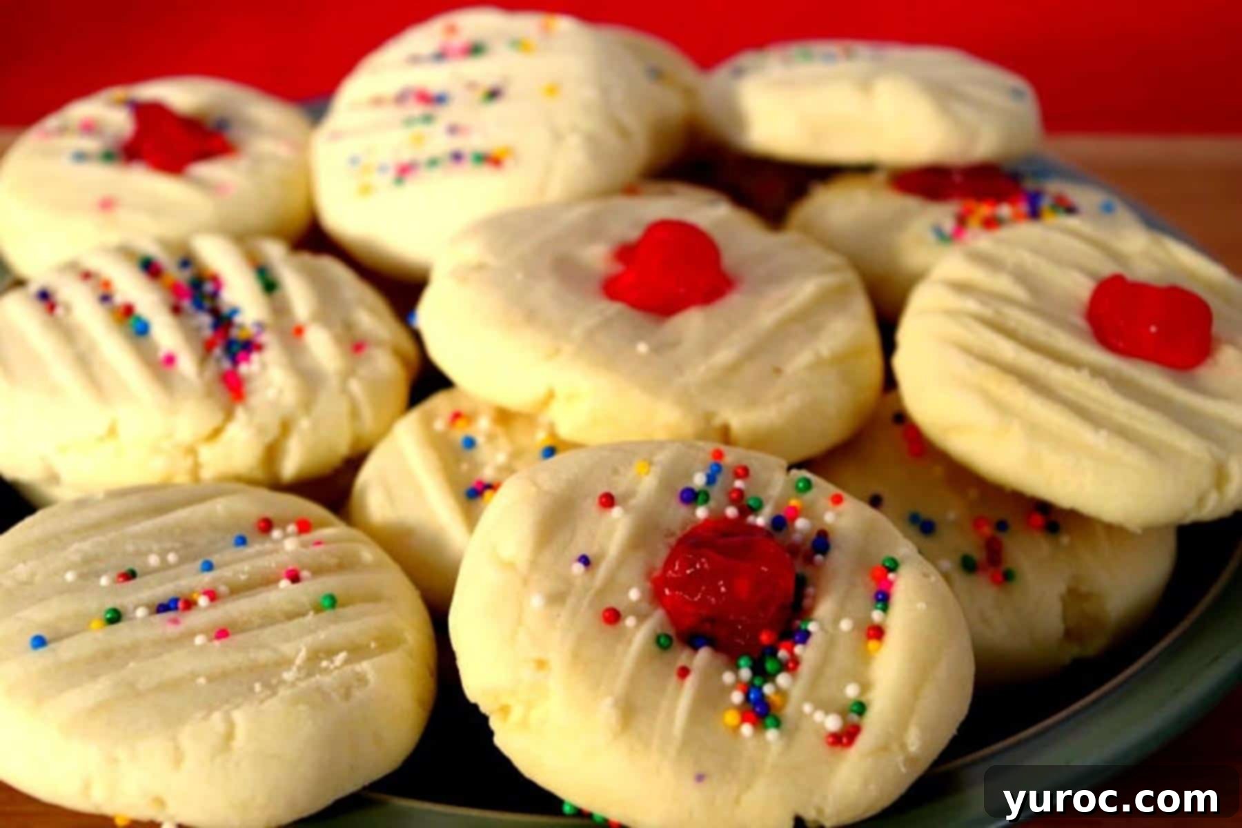 4 ingredient whipped shortbread piled on a plate with red background