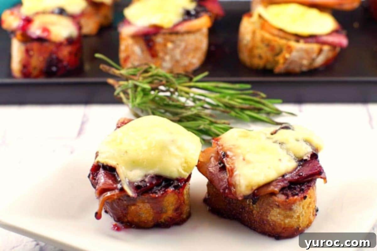 A close-up shot of golden-brown Turkey Brie Bites arranged on a serving platter, garnished with fresh rosemary.