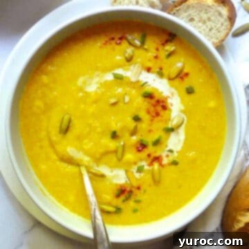 Creamy Butternut Squash and Corn Soup served in a white bowl with a spoon, highlighting its smooth texture and rich color.