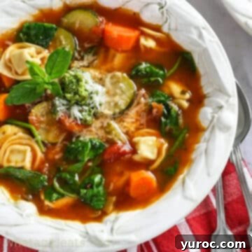 Spinach Tortellini Soup served in a white bowl with a spoon resting on the side, highlighting the pasta and vibrant green spinach.