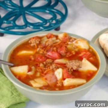 Hearty Hamburger Potato Soup served in a green bowl, with a pot holder visible in the soft-focus background.