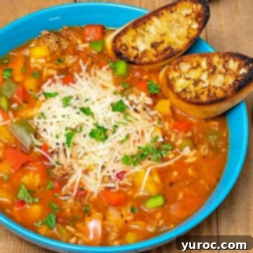 Easy Stuffed Pepper Soup served in a blue bowl, with a slice of garlic bread resting on the side of the soup bowl.
