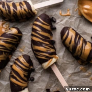 Frozen chocolate-covered bananas arranged neatly on parchment paper.