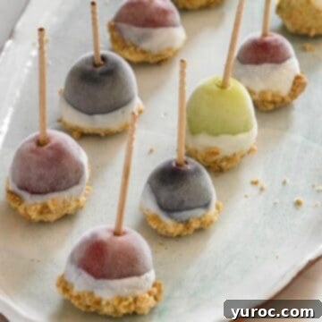 Yogurt-dipped frozen grapes arranged in two neat lines on a clean white plate.