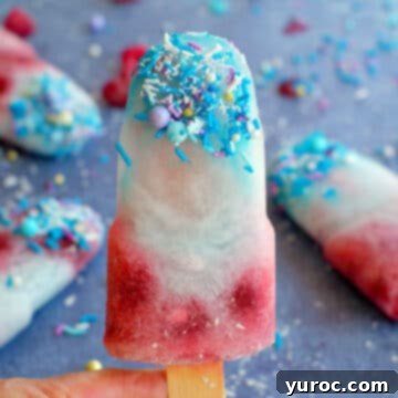 A vibrant blue raspberry popsicle held up, with more popsicles visible in the background.