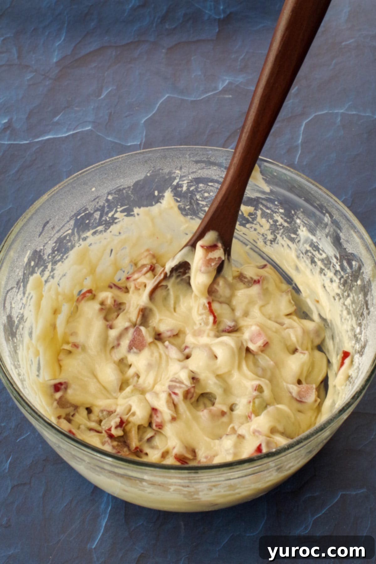 rhubarb folded into cake batter, with dark wooden spoon