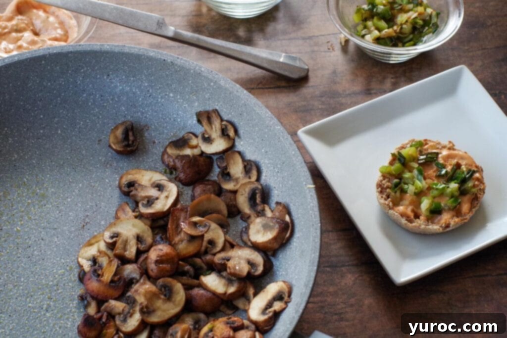 Cooked green onions placed on top of the Dijon-sauced English muffin halves.