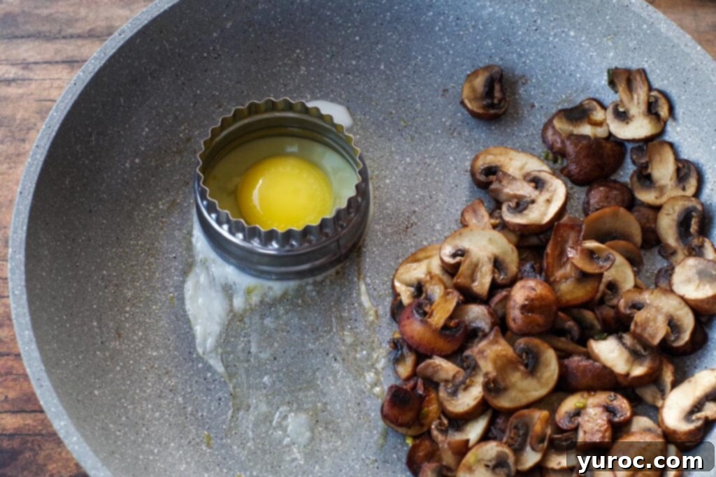 Eggs cooking in a skillet, some perfectly round using a cookie cutter, while mushrooms continue to sauté.