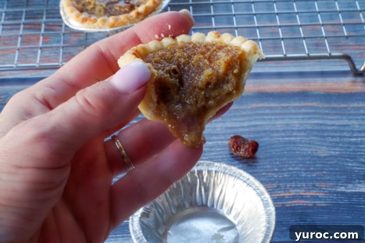 butter tart being held up with filling seeping out