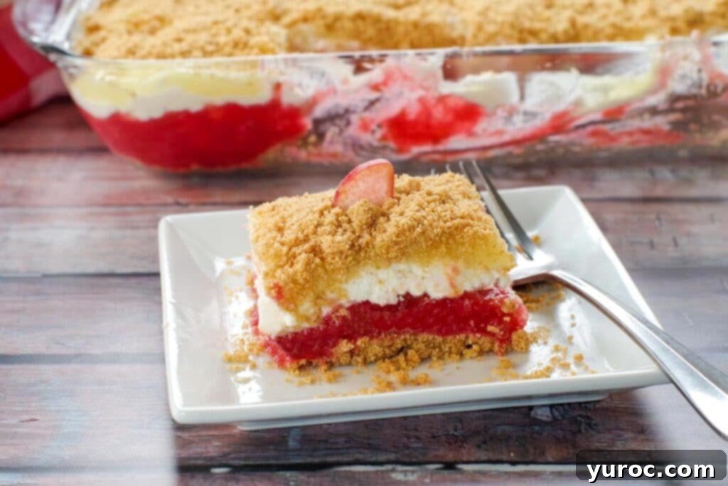 No-Bake Rhubarb Delight 2 Rhubarb dessert on a white plate with fork on the right side and pan of more dessert in the background