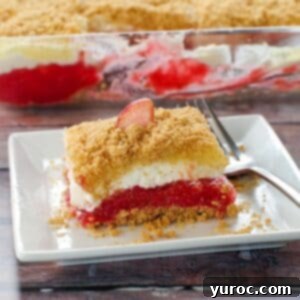 No-Bake Rhubarb Delight 16 Rhubarb dessert on a white plate with fork on the right side and pan of more dessert in the background