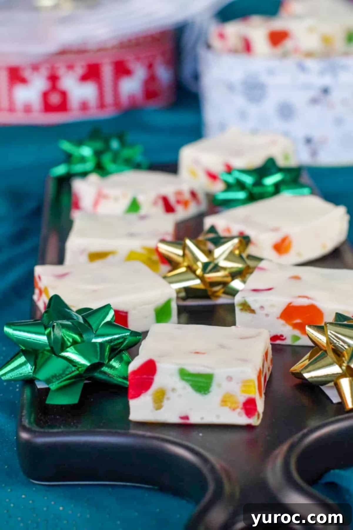 Christmas Nougat Candy on narrow black serving platter with bows and cookie tins in the background, ready for a festive gathering