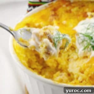 frozen perogy breakfast casserole om a white casserole dish, with a spoonful being held up. A golden-brown Pierogi Breakfast Casserole, served hot from a white dish with a spoonful being lifted.