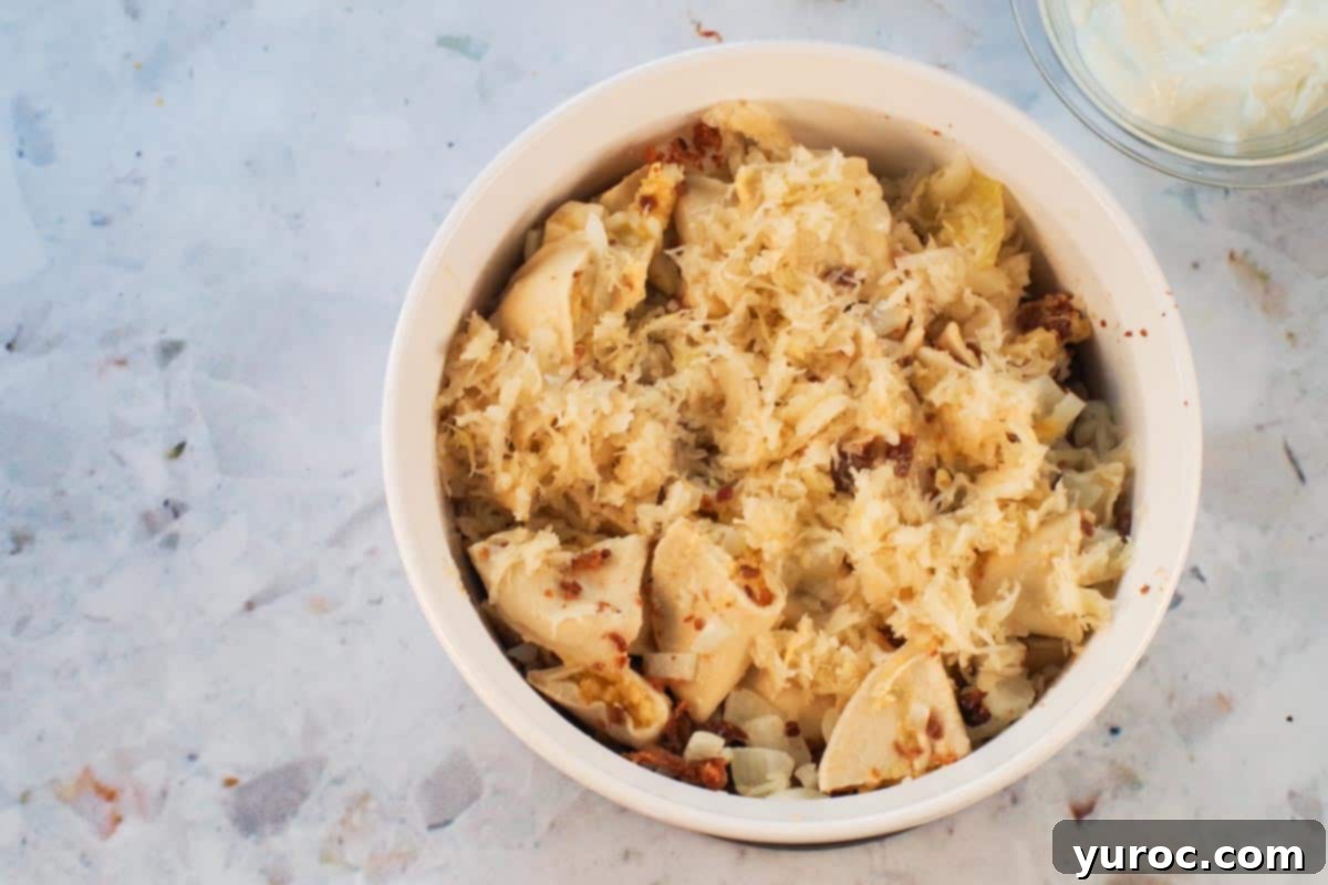 Sauerkraut added to perogies and bacon bits in white casserole dish. Finely chopped and drained sauerkraut spread over the pierogies and bacon.