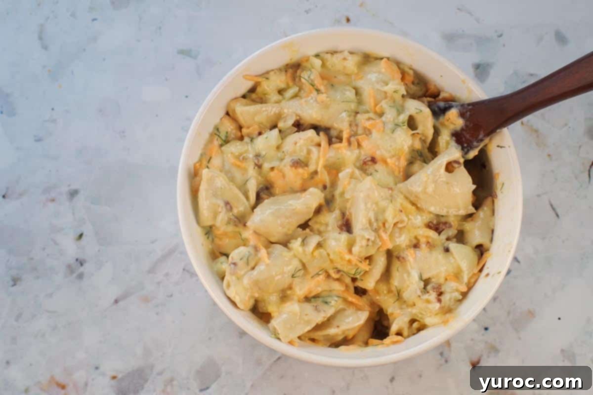 Egg mixture poured over perogies and gently stirred in. The creamy egg mixture is being distributed over the pierogies and other ingredients.