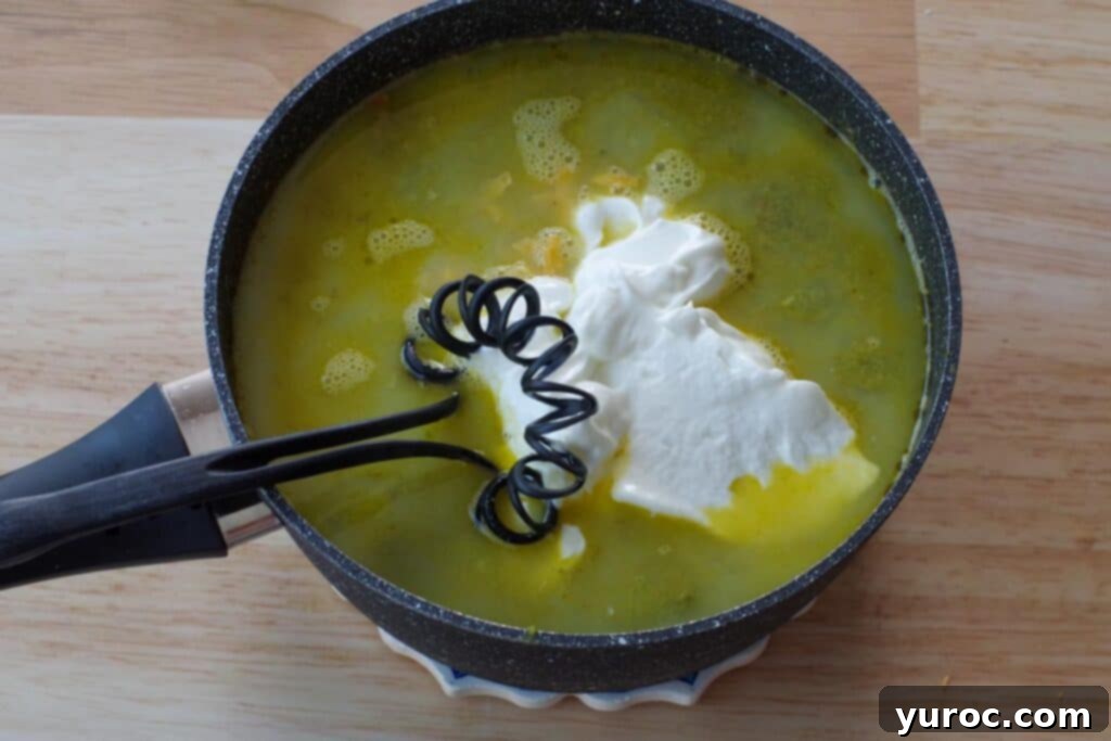 Low-fat cheese, Greek yogurt, and milk being whisked into the soup off the heat.
