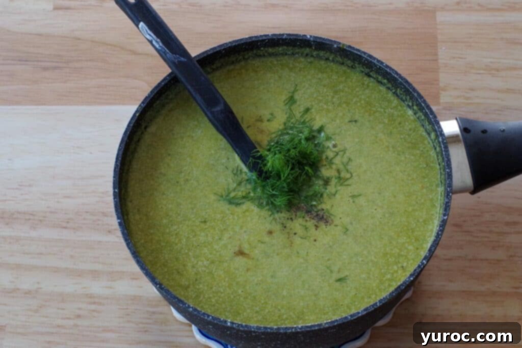 Fresh dill being stirred into the finished creamy fiddlehead soup.