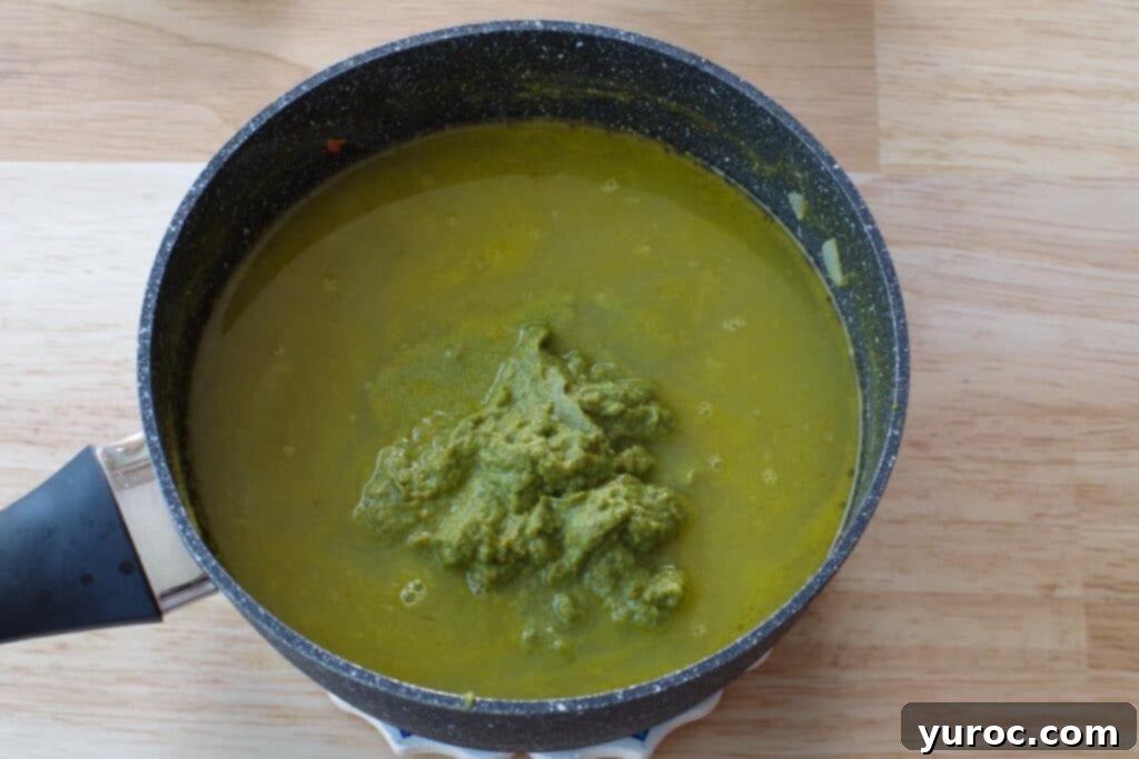 The smooth vegetable puree being whisked back into the soup in the pot.