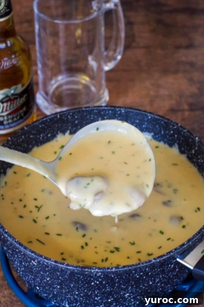 Effortless Beer Cheese Soup 11 A ladle serving a generous portion of creamy Beer Cheese Soup with Cheez Whiz from a large pot, emphasizing the soup's rich texture and comforting appeal, ready to be enjoyed.