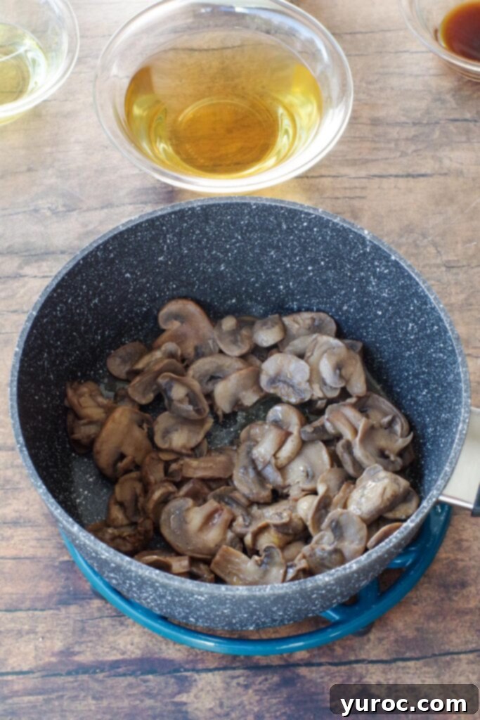 Effortless Beer Cheese Soup 3 Sliced mushrooms being sautéed with butter and seasoning salt in a large cooking pot on a stovetop, capturing the initial stage of softening and infusing flavor.