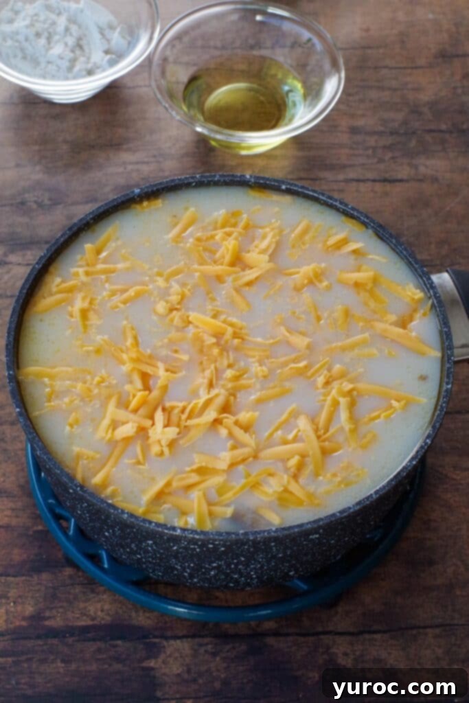 Effortless Beer Cheese Soup 4 Various soup ingredients including liquids, cheese, and seasonings being combined in a large pot on the stove, ready for whisking and heating. The scene illustrates the initial mixing phase of soup preparation.