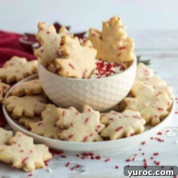 maple shaped cookies with cream cheese dip in a white bowl, with red sprinkles all around
