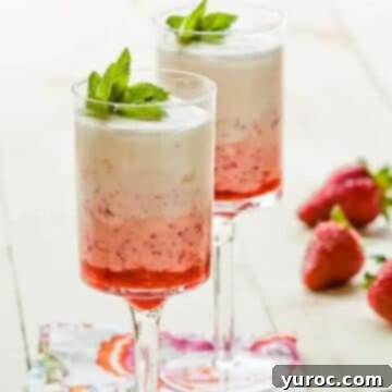2 strawberry fool parfaits in tall parfait glasses with whole strawberries in the background