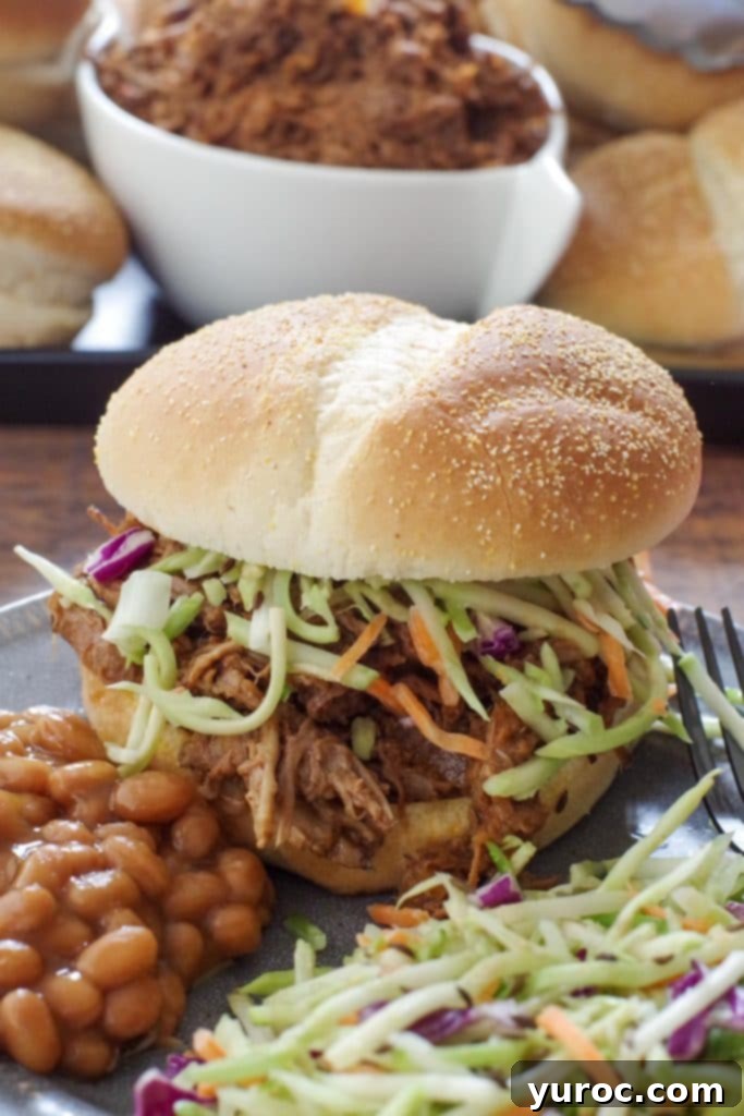 beef on a bun on a grey plate with coleslaw and beans