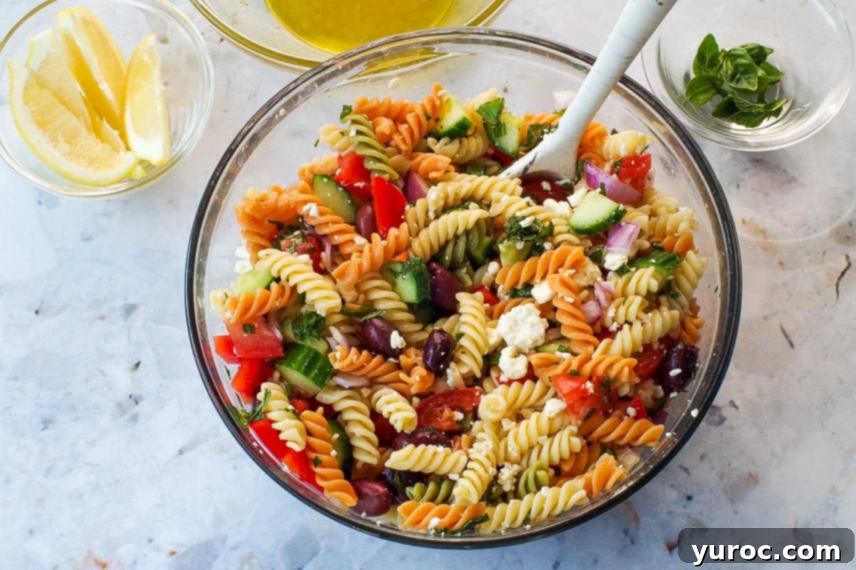 Remaining ingredients added to pasta in large glass bowl with spoon.
