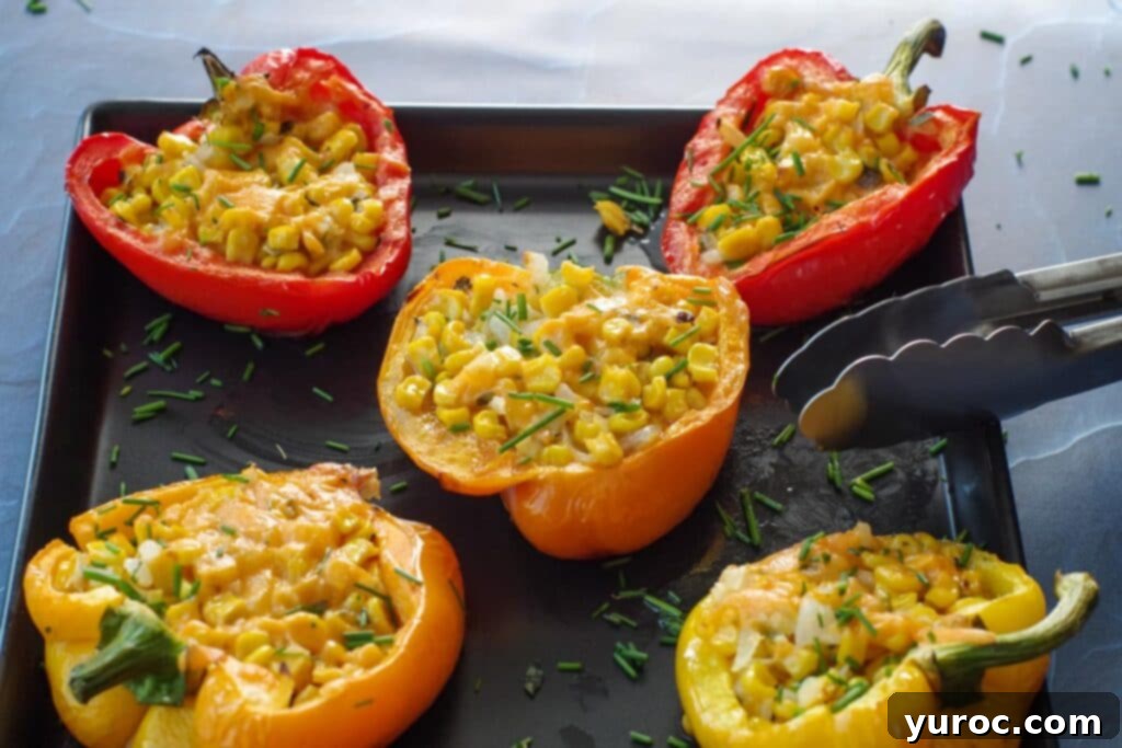 5 Stuffed grilled peppers on a black platter with thongs