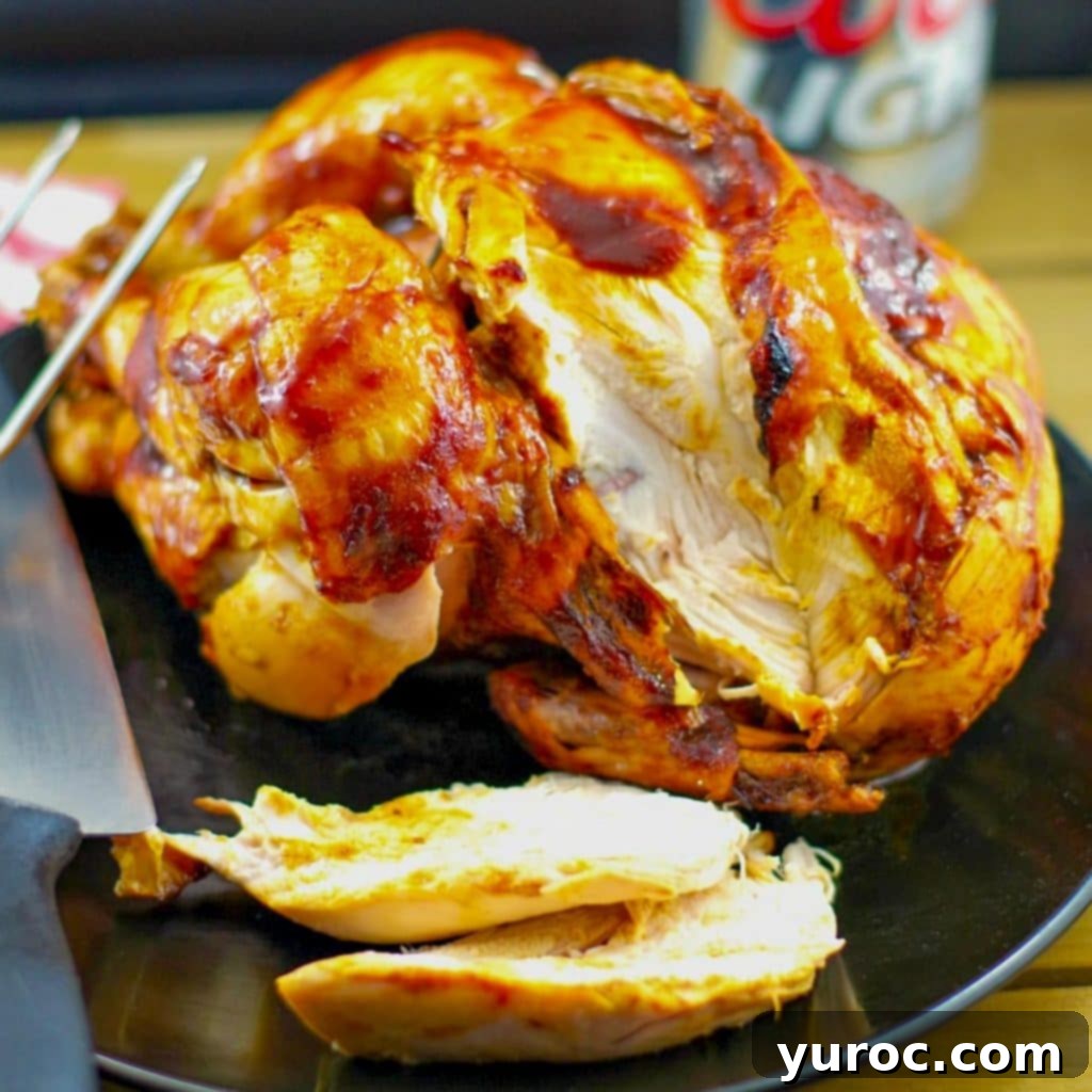 WW BBQ beer can chicken on a black serving plate with a knife and can of beer in the background