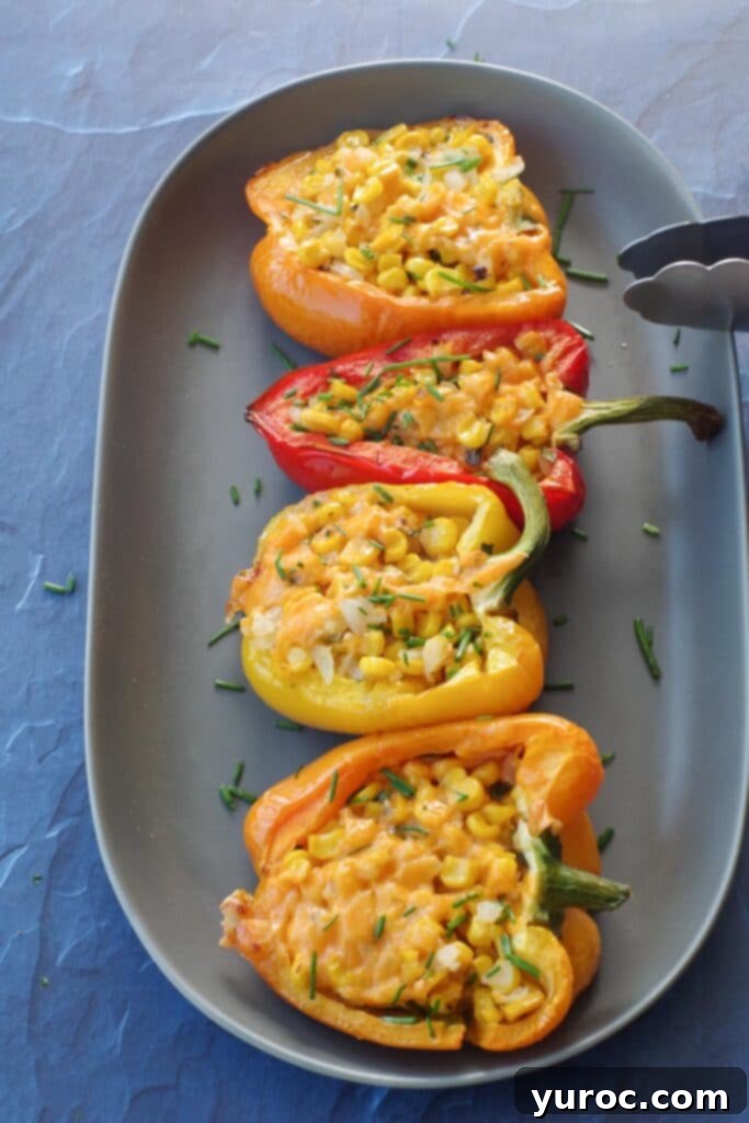 4 stuffed grilled peppers on a long grey platter with thongs leaning on platter