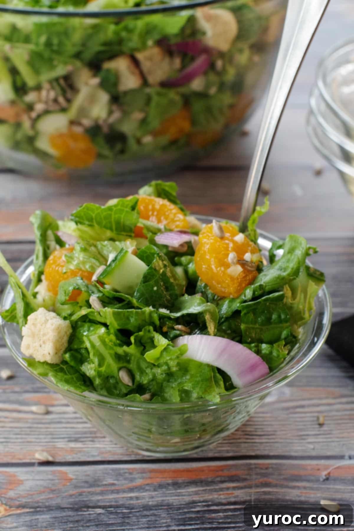 Mandarin Orange salad in a small glass bowl with a fork, with a large glass bowl of salad in the background, ready for serving.