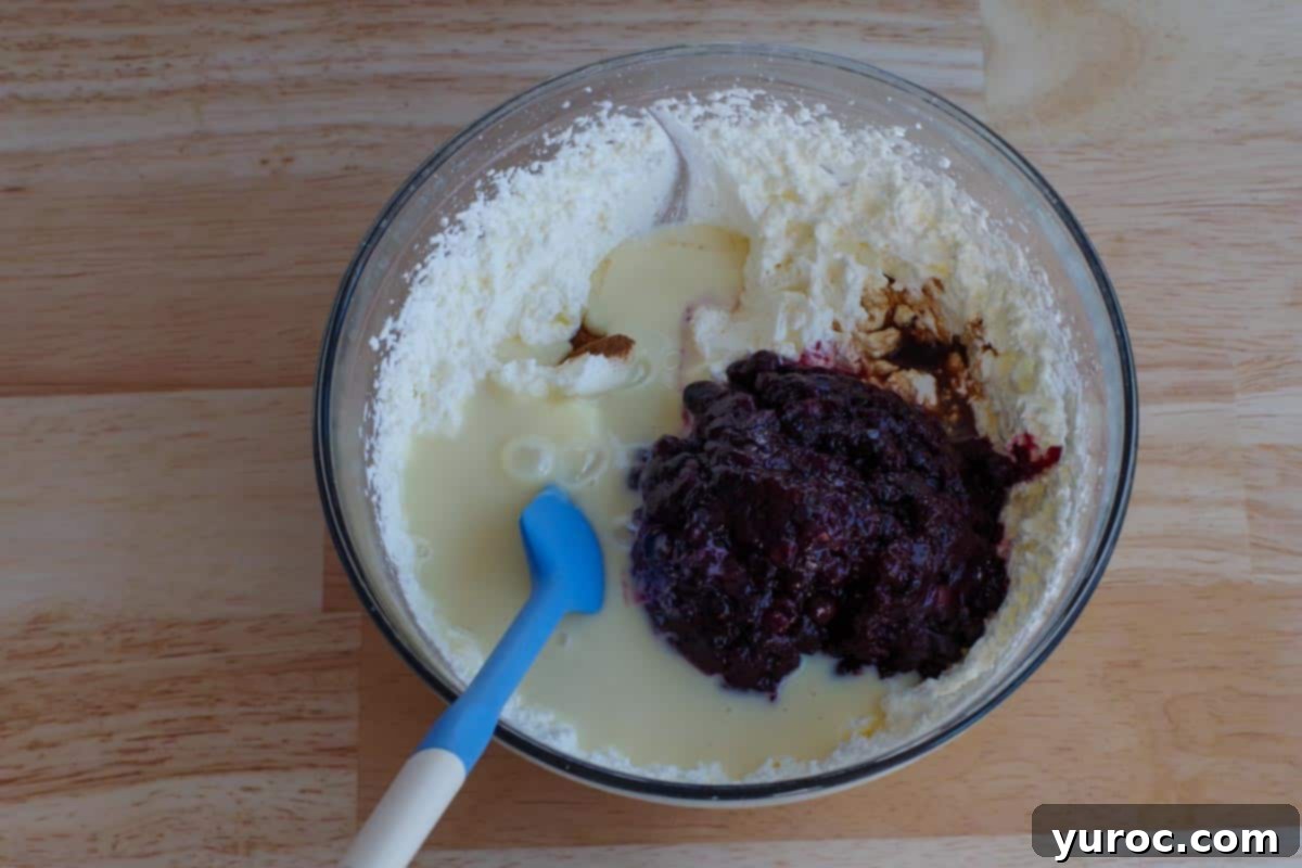 whipped cream with other ingredients added in bowl, including saskatoon berry sauce, extracts, and condensed milk