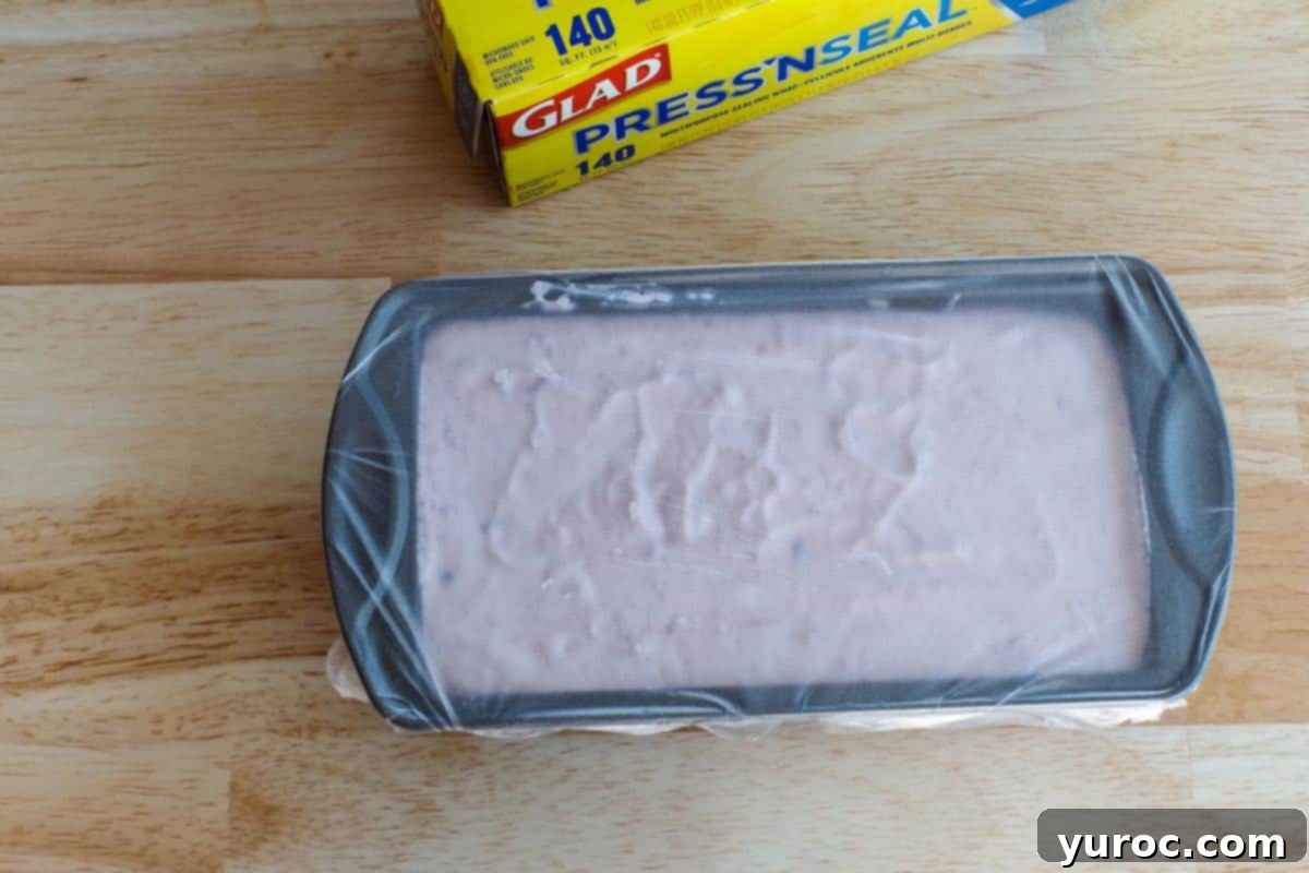 plastic covered loaf pan with ice cream mixture inside, sealed for freezing