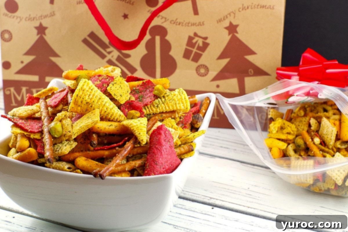Christmas Chex Mix in a white bowl with a festive Christmas bag in the background, showing vibrant red and green colors