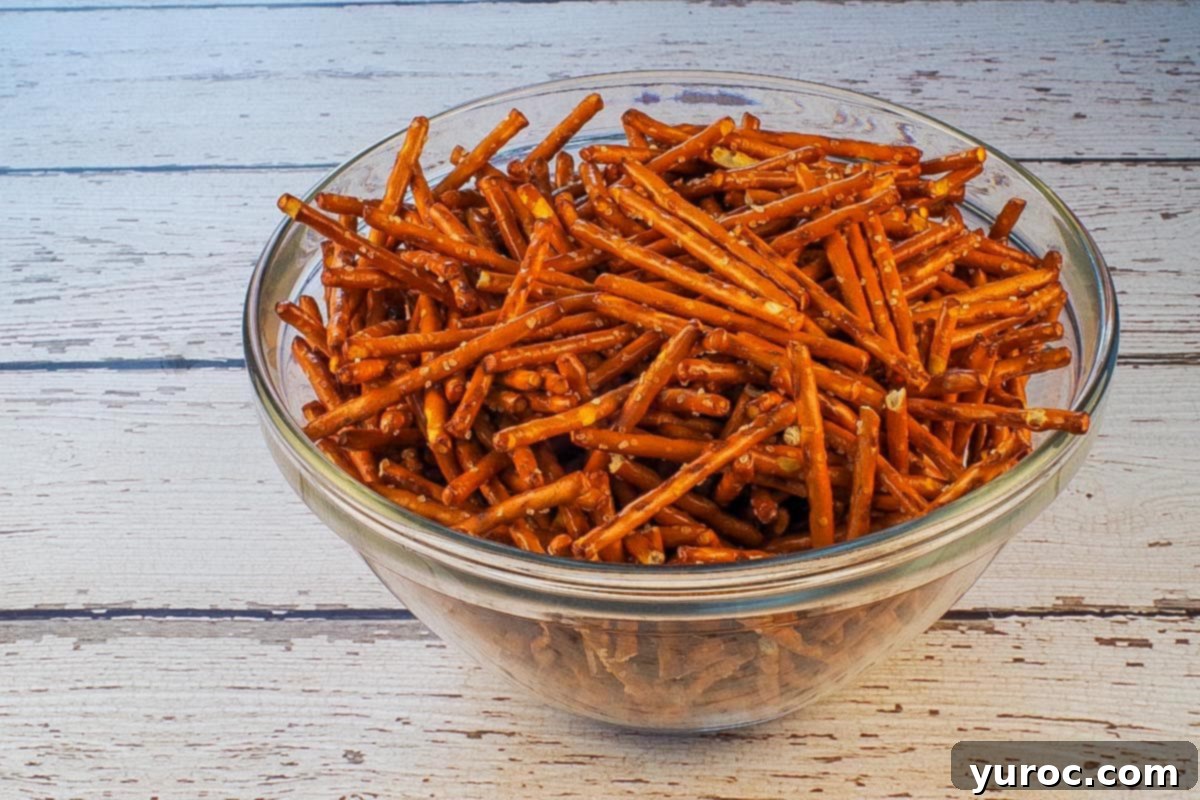 Close-up of pretzel sticks in a clear glass bowl, ready to be added to the snack mix