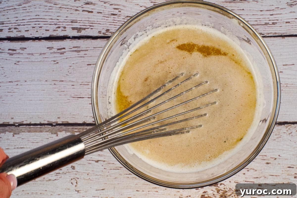 Melted butter in a glass bowl with a metal whisk, ready to be combined with ranch seasoning and Worcestershire sauce.