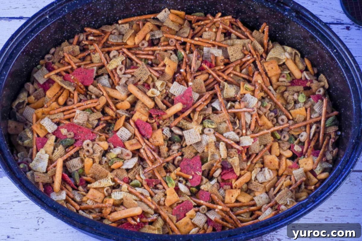 The baked savory snack mix in a large oval roasting pan, golden brown and ready for cooling and serving.