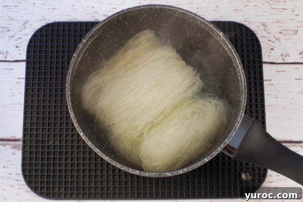 Honey Fire Chicken Lettuce Embrace 7 Vermicelli noodles soaking in hot water in saucepan.