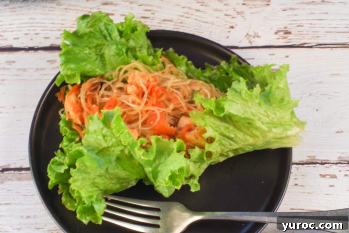 Honey Fire Chicken Lettuce Embrace 10 Spicy chicken lettuce wrap on a black plate with a fork.