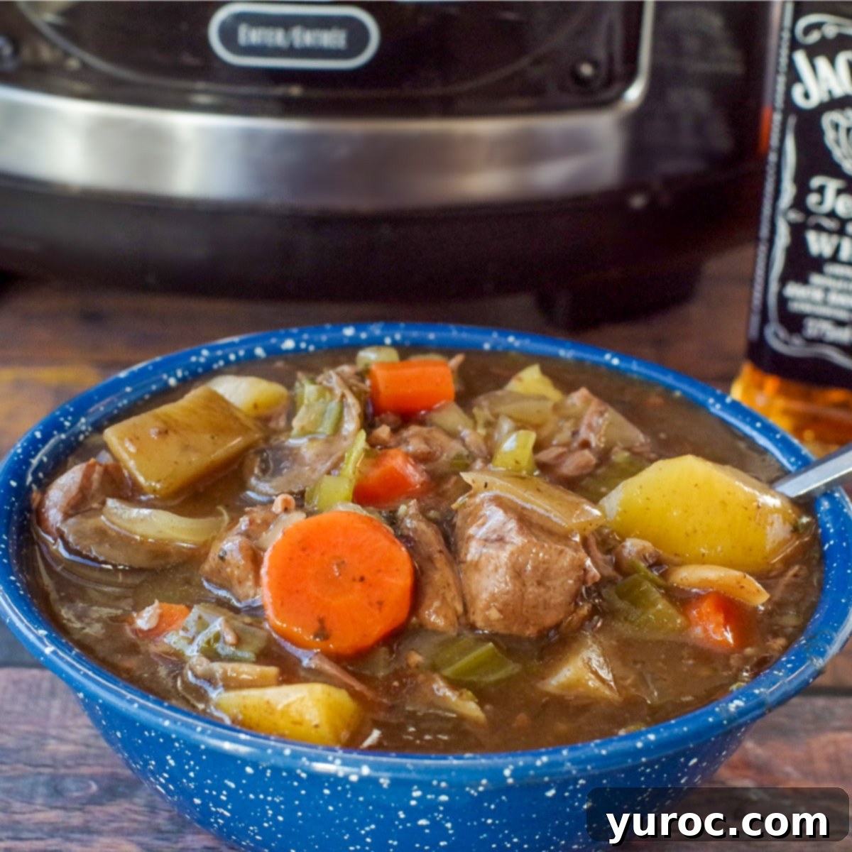 slow cooker beef stew in a blue bowl with slow cooker in the background