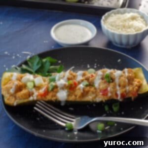 buffalo chicken zucchini boats with ranch dip and parmesan cheese in white bowls in the background