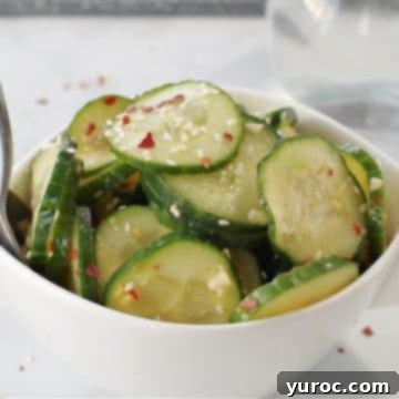 kimchi pickle in white bowl on grey marble counter surface with glass vinegar container in background