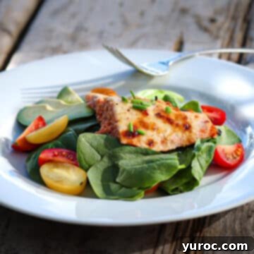miso salmon on a bed of lettuce and vegetables in a white bowl