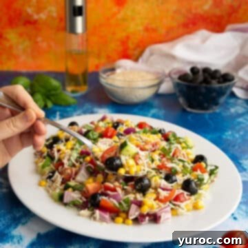 Italian rice salad on a white plate with hand holding fork in salad