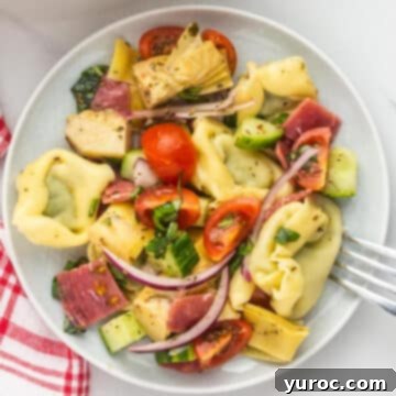 Tortellini salad on a white plate with a fork