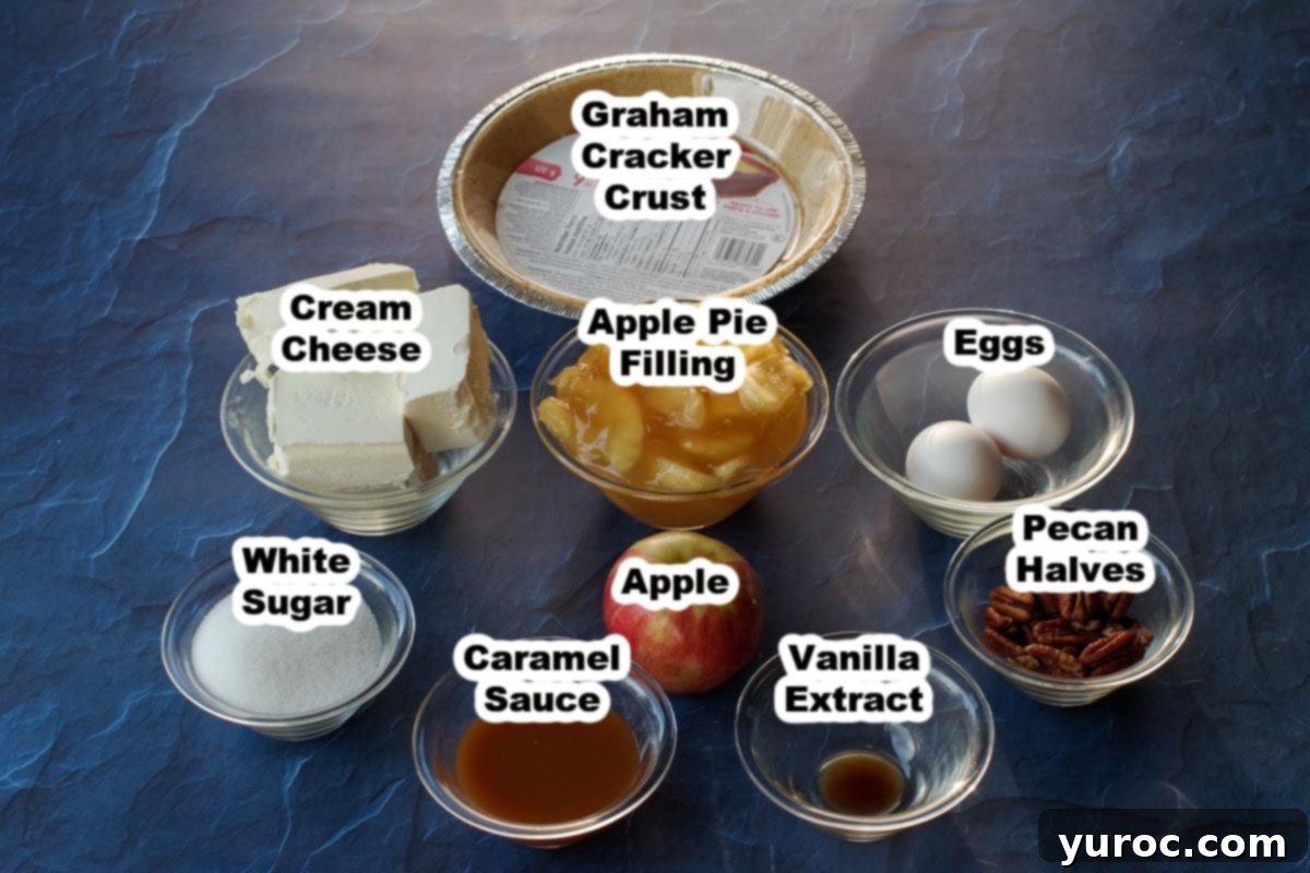 Labeled ingredients for Caramel Apple Cheesecake Pie in clear glass bowls, including apple pie filling, cream cheese, caramel sauce, pecans, and a fresh apple.