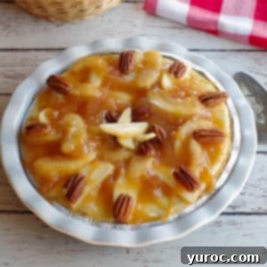 A whole caramel apple cheesecake pie on a white wooden background with a red checkered cloth in the background, highlighting its delicious appeal.